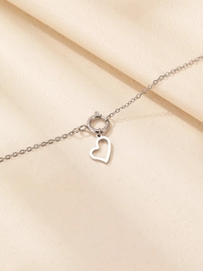 Dettaglio ravvicinato di un ciondolo a cuore argento su una catena sottile con chiusura a molla