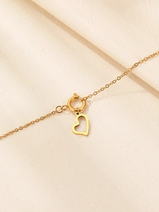 Dettaglio ravvicinato di una collana a catena dorata con ciondolo a cuore traforato