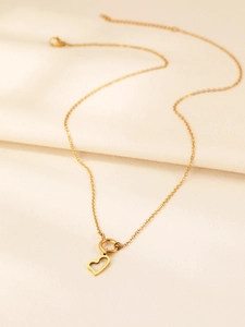 Dettaglio della collana con ciondolo a cuore dorato e chiusura a levetta OT su raso morbido