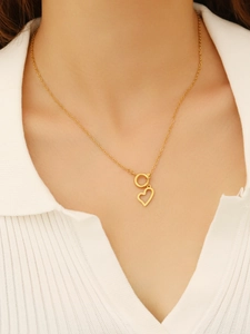 Dettaglio della collana dorata con ciondolo a cuore e chiusura OT indossata da una modella