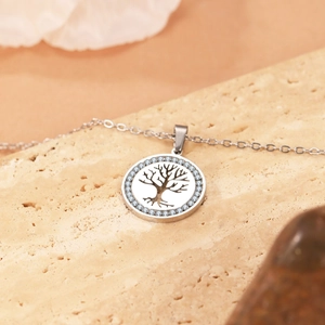 Collana con moneta albero della vita argento con zirconi azzurri su fondo di marmo