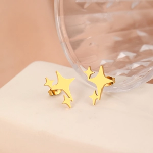 Minimalist gold stainless steel star stud earrings on a modern white display stand