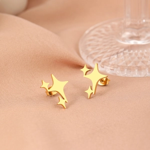Detailed view of gold stainless steel four-pointed star stud earrings on soft fabric
