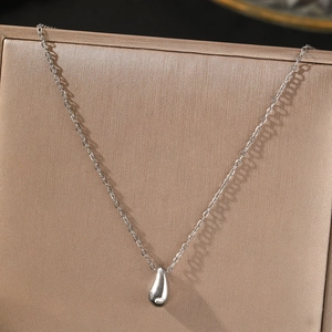 Détail d'un pendentif goutte d'eau sur une chaîne fine posée sur un coffret à bijoux