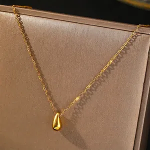Gros plan d'un pendentif goutte doré sur une chaîne fine en acier titane élégante