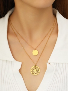 Close-up of double-layered gold necklace with solid coin and hollow floral pendant