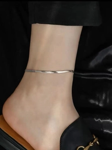 Close-up of minimalist silver stainless steel snake chain anklet on woman's ankle