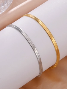 Macro shot of 18K gold and silver flat snake chains with polished scale texture