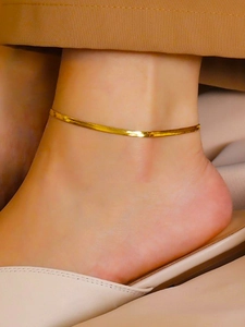 Close-up of minimalist flat snake blade chain anklet in 18K gold plated stainless steel