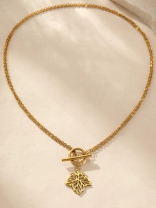 Macro detail of gold maple leaf pendant with chunky chain and classic OT toggle clasp