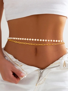 Close-up of double-layer gold chain with white pearls on woman's waist and jeans