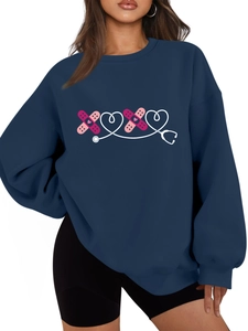 Dettaglio felpa blu scuro oversize con grafica a cuore stetoscopio e cerotto medico