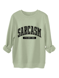Detail view of sage green sweatshirt featuring black Sarcasm slogan text and ribbed cuffs