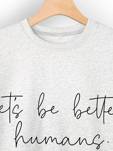 Detail of grey sweatshirt showing ribbed crewneck and let's be better humans print