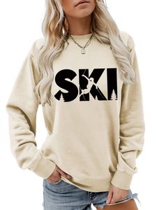 Close-up of the SKI letter print with skier and pine tree details on a beige sweatshirt