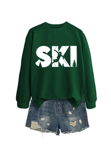 Flat lay of a green SKI sweatshirt paired with distressed blue denim shorts