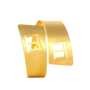 Polished gold napkin ring featuring a cutout F-shaped pattern for elegant wedding decor