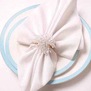 Elegant gold napkin ring with crystal snowflake detail on luxury ceramic dinnerware