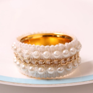 Detail of DIY pearl chain napkin ring with white lace fabric and gold metal plating