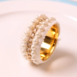 Elegant gold napkin ring with white tweed texture, pearls and delicate chain detail