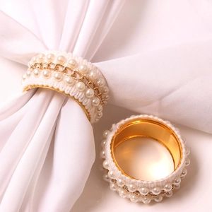 Detailed view of elegant gold pearl napkin rings with lace weaving and metal chains
