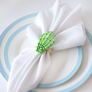 Macro view of neon green skeleton hand napkin ring with gold metal band on table