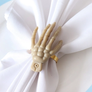Detailed close-up of a realistic bone skeletal hand napkin ring on a white plate