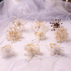 Elegant beaded napkin rings with pearl floral and snowflake designs on gold metal bands