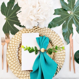 Handmade eucalyptus leaf napkin ring with wood bead on a blue fabric napkin