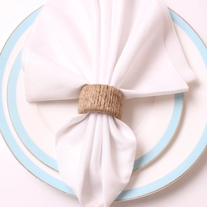 Detailed top view of a handmade rustic jute napkin ring on a white napkin and blue plate