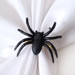 Halloween spider napkin ring with black spider and gold metal ring on white fabric