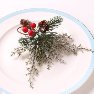 Christmas napkin ring with pine cones red berries and snow cedar on a ceramic plate