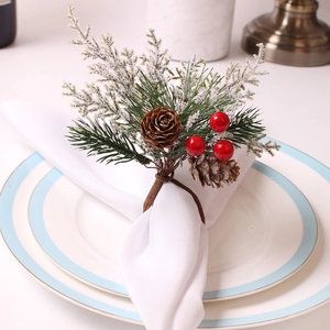 Christmas napkin ring featuring pine needles, pine cones and red berries on white plate