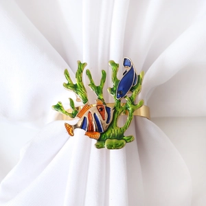 Golden sea life napkin ring featuring green coral and colorful tropical fish on white fabric