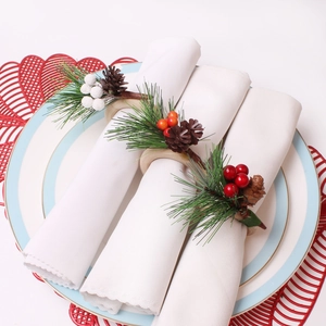 Weihnachtliche Serviettenringe mit roten Beeren und Tannenzapfen für die Tischdekoration
