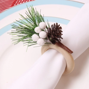 Weihnachtlicher Serviettenring mit roten Beeren und Piniennadeln auf weißem Porzellan