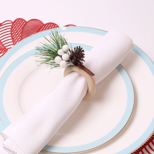 Detail von Weihnachts-Serviettenring mit Tannenzapfen und Beeren auf weißer Serviette