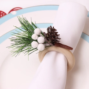 Detailaufnahme eines Weihnachts-Serviettenrings mit Tannenzapfen und weißen Beeren