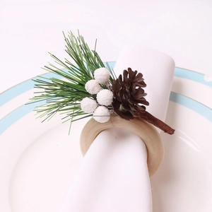 Detail eines Weihnachts-Serviettenrings mit Tannennadeln, weißen Beeren und Zapfen