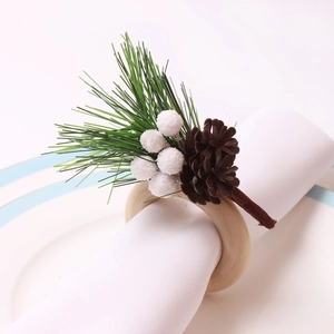 Detail eines hölzernen Serviettenrings mit Tannenzapfen und weißen Beeren für Weihnachten