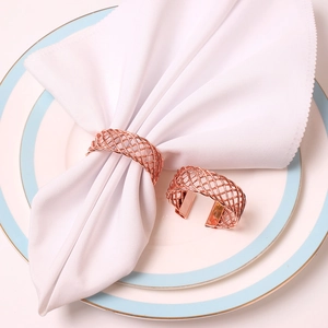 Close-up of woven mesh napkin rings in rose gold finish for elegant table setting
