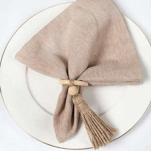 Natural wood napkin ring with jute tassel and wooden bead on elegant white ceramic plate