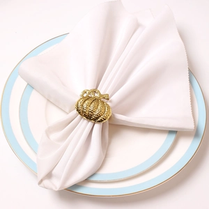 Servilletero de calabaza dorada martillada sobre plato blanco para decorar la mesa