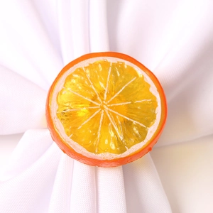Realistic orange lemon slice napkin ring accessory on a white cloth napkin
