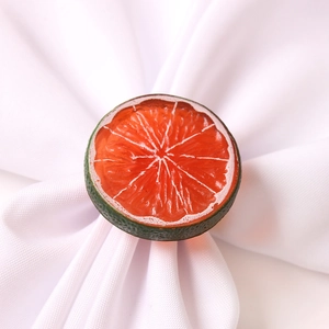Lifelike orange slice napkin ring on a white fabric napkin for dining table decoration