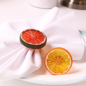 Realistic orange and lemon slice napkin rings with gold metal bands on table
