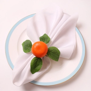 Detailed close-up of realistic orange napkin ring with green leaves on white ceramic plate