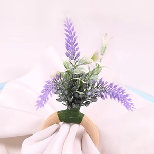 Detail eines Lavendel-Serviettenrings mit lila Kunstblumen auf einem hellen Holzring