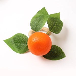 Detail of woven rattan napkin ring featuring realistic faux orange fruit and green leaves