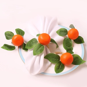 Detail showing a set of four realistic artificial orange napkin rings on a ceramic plate